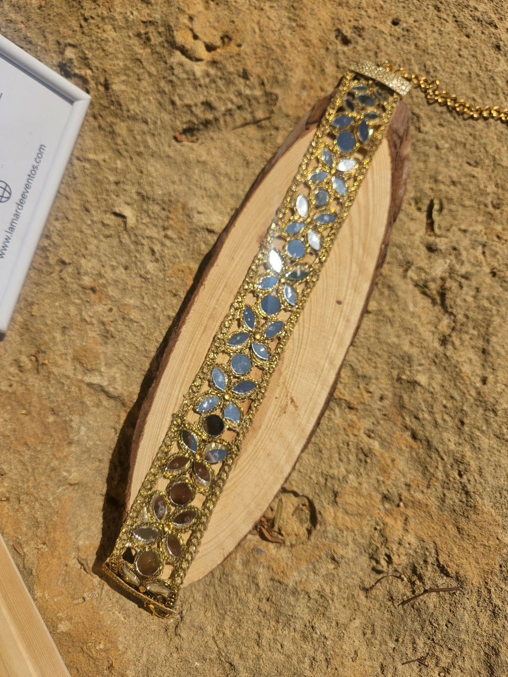 Collar tipo choker dorado con pedrería azul y detalles calados, banda ancha