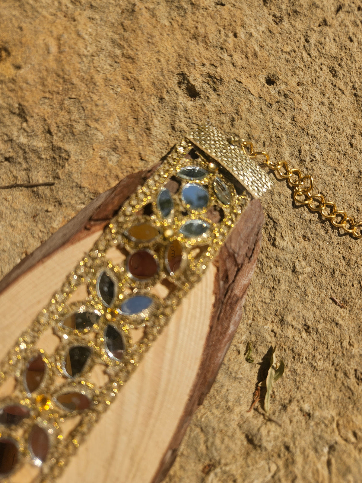 Collar tipo choker dorado con pedrería azul en patrón floral, vista lateral