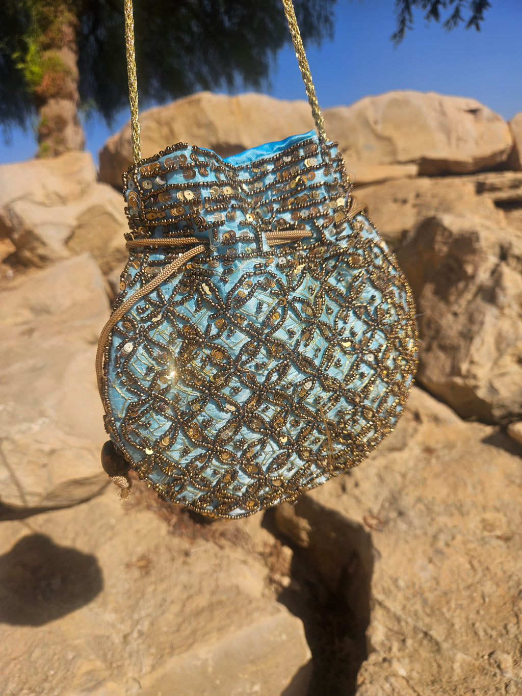 Bolso de saco bordado con lentejuelas doradas y turquesa, con cordón superior.