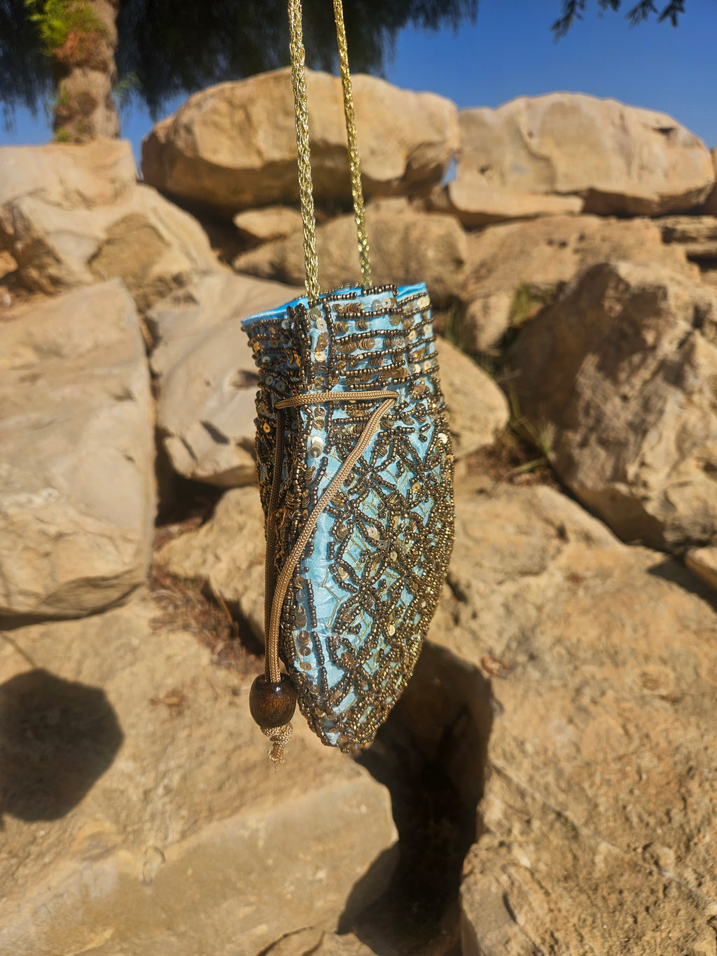 Bolso de saco turquesa y dorado con bordado texturizado y asa de cadena.