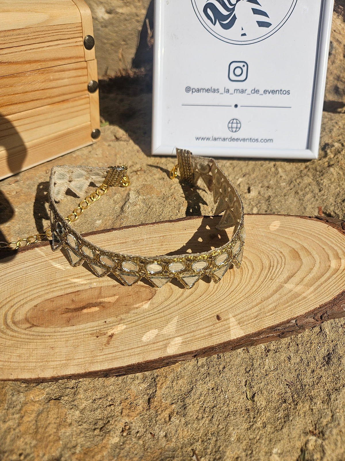 Collar choker dorado con pedrería azul, visto desde arriba sobre base de madera