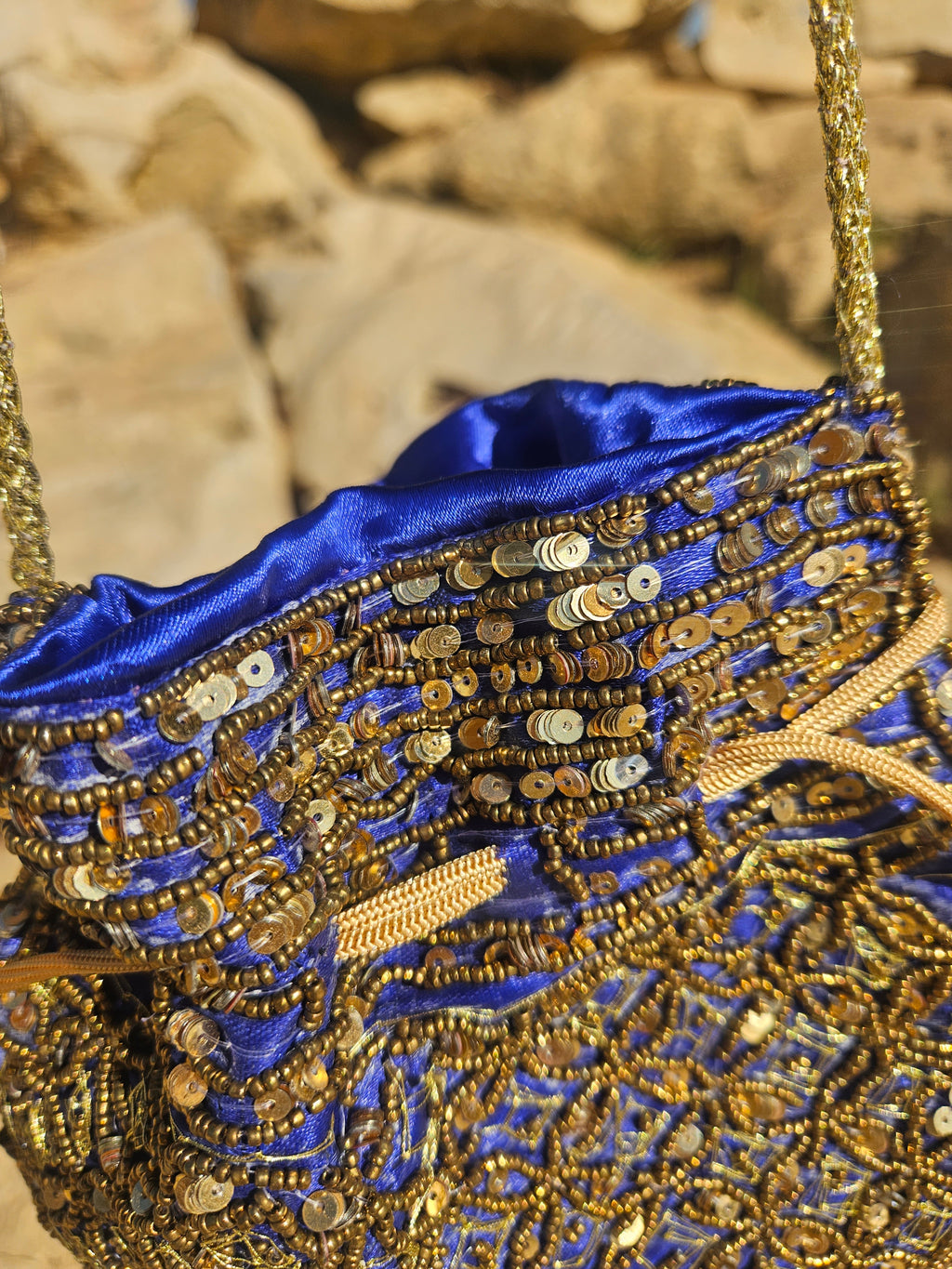 Bolso bordado azul y dorado con cierre superior y forro azul satinado visible