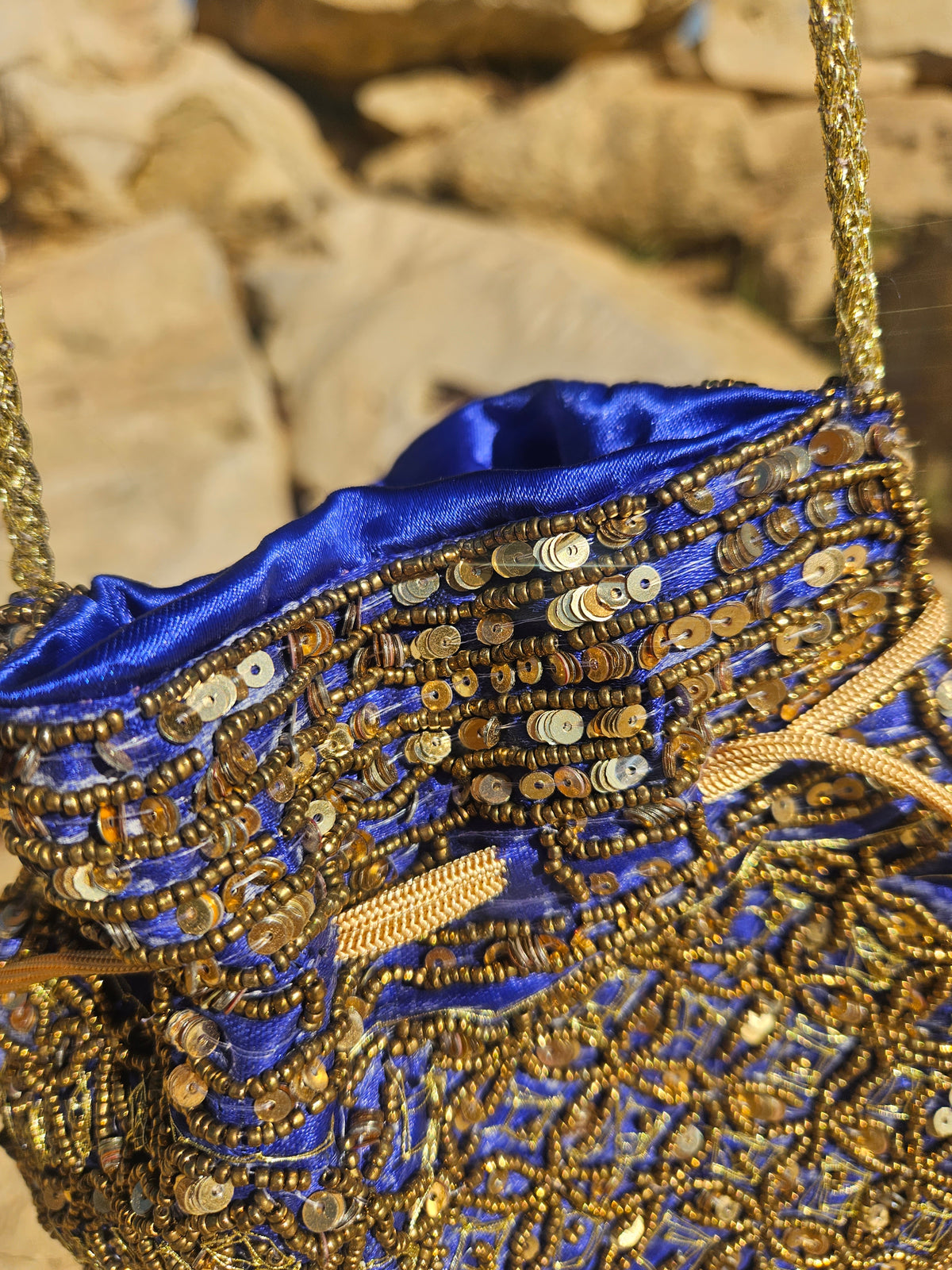Bolso bordado azul y dorado con cierre superior y forro azul satinado visible