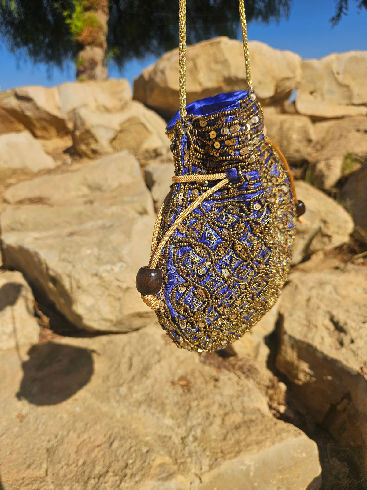 Bolso redondo azul y dorado con asa de cadena, vista lateral y forro azul