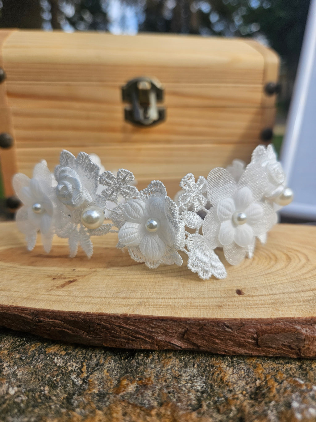 Choker de encaje blanco con flores y perlas, vista lateral sobre base de madera