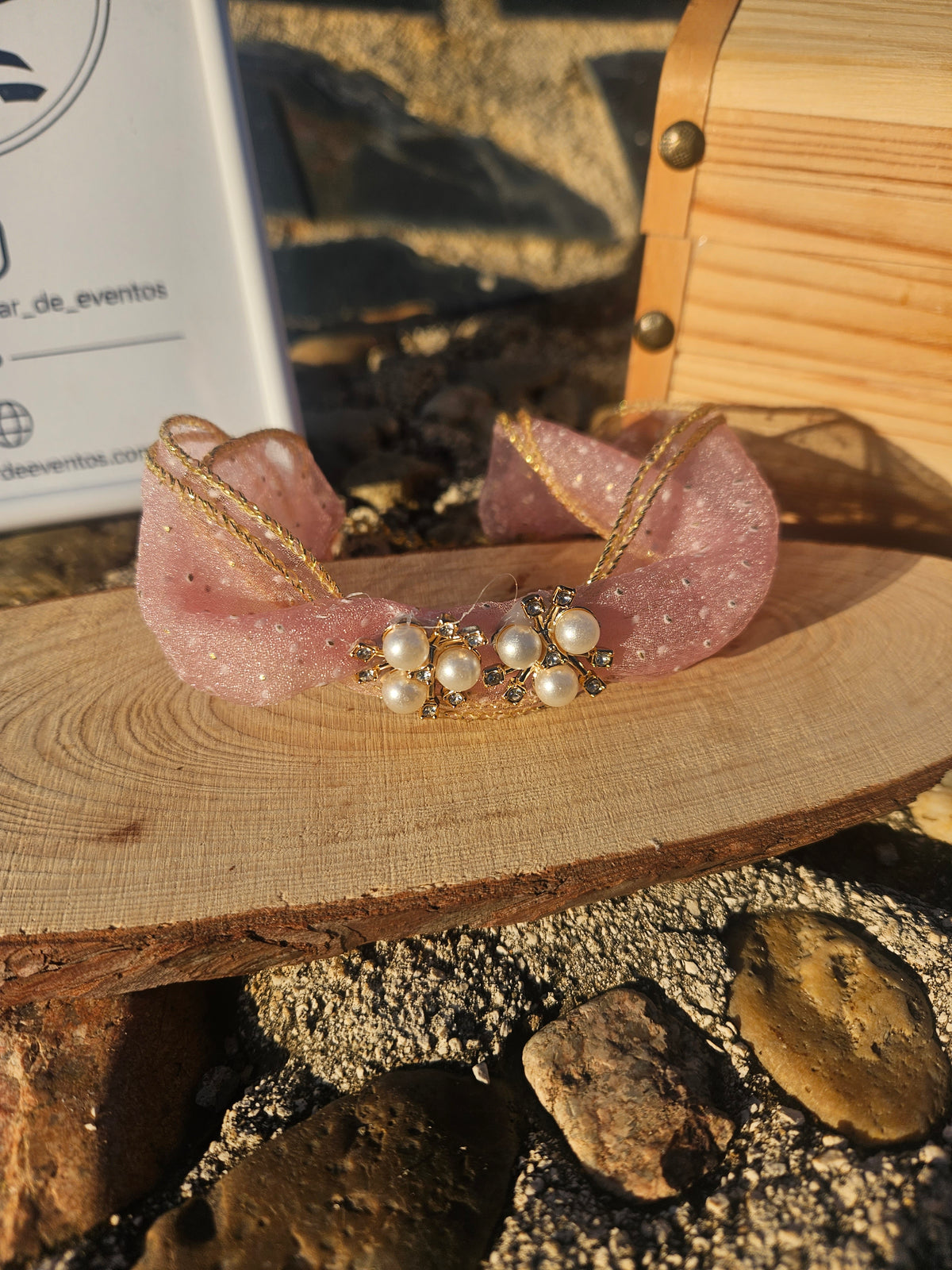 Choker rosa con lazo de tul y centro de perlas, rodeado de pedrería.