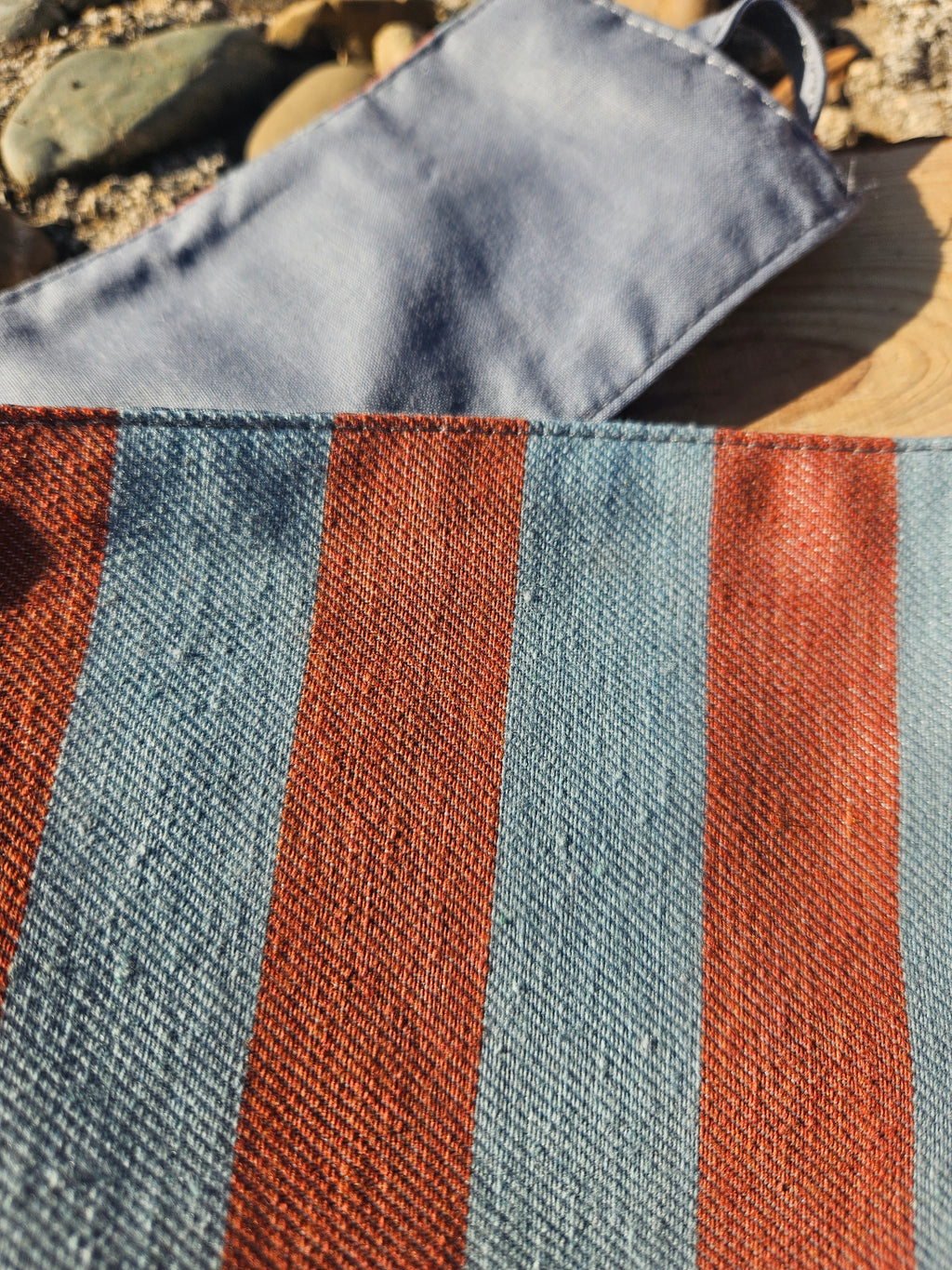 Detalle del fajín de rayas Atenas: textura de tela azul y naranja, costuras