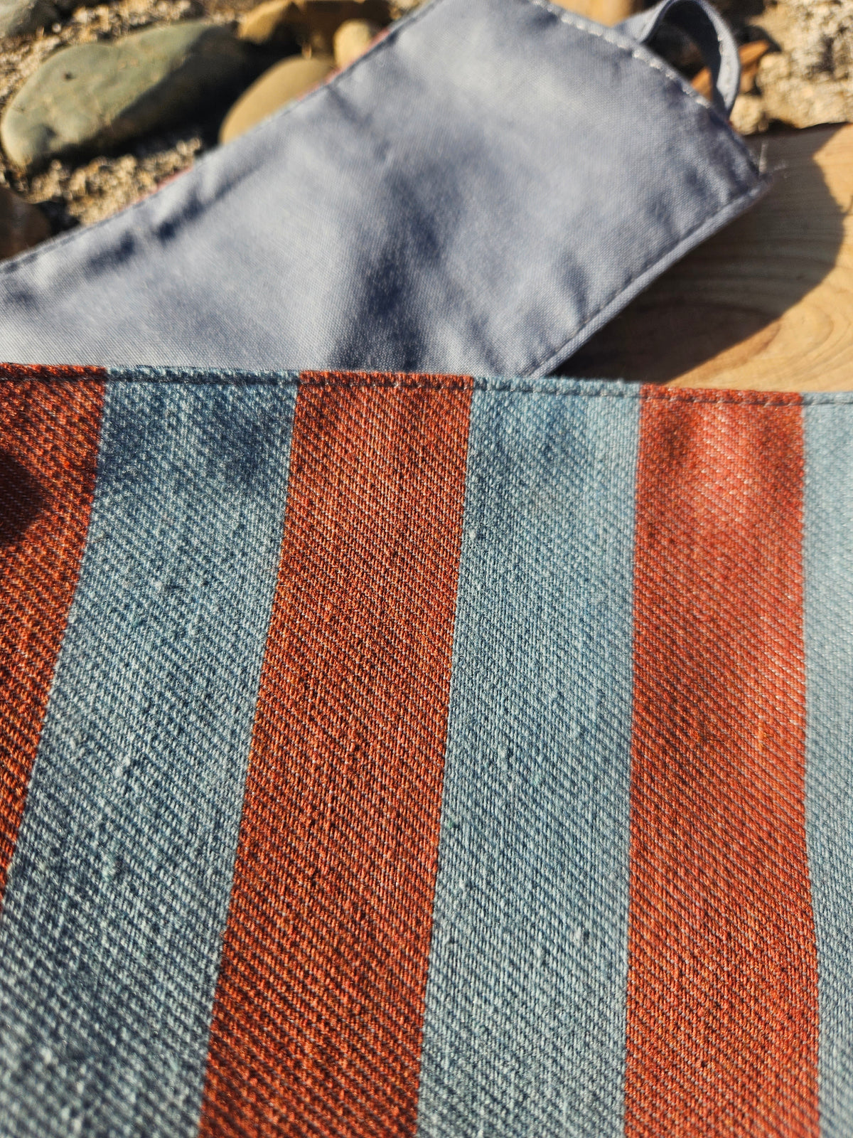 Detalle del fajín de rayas Atenas: textura de tela azul y naranja, costuras