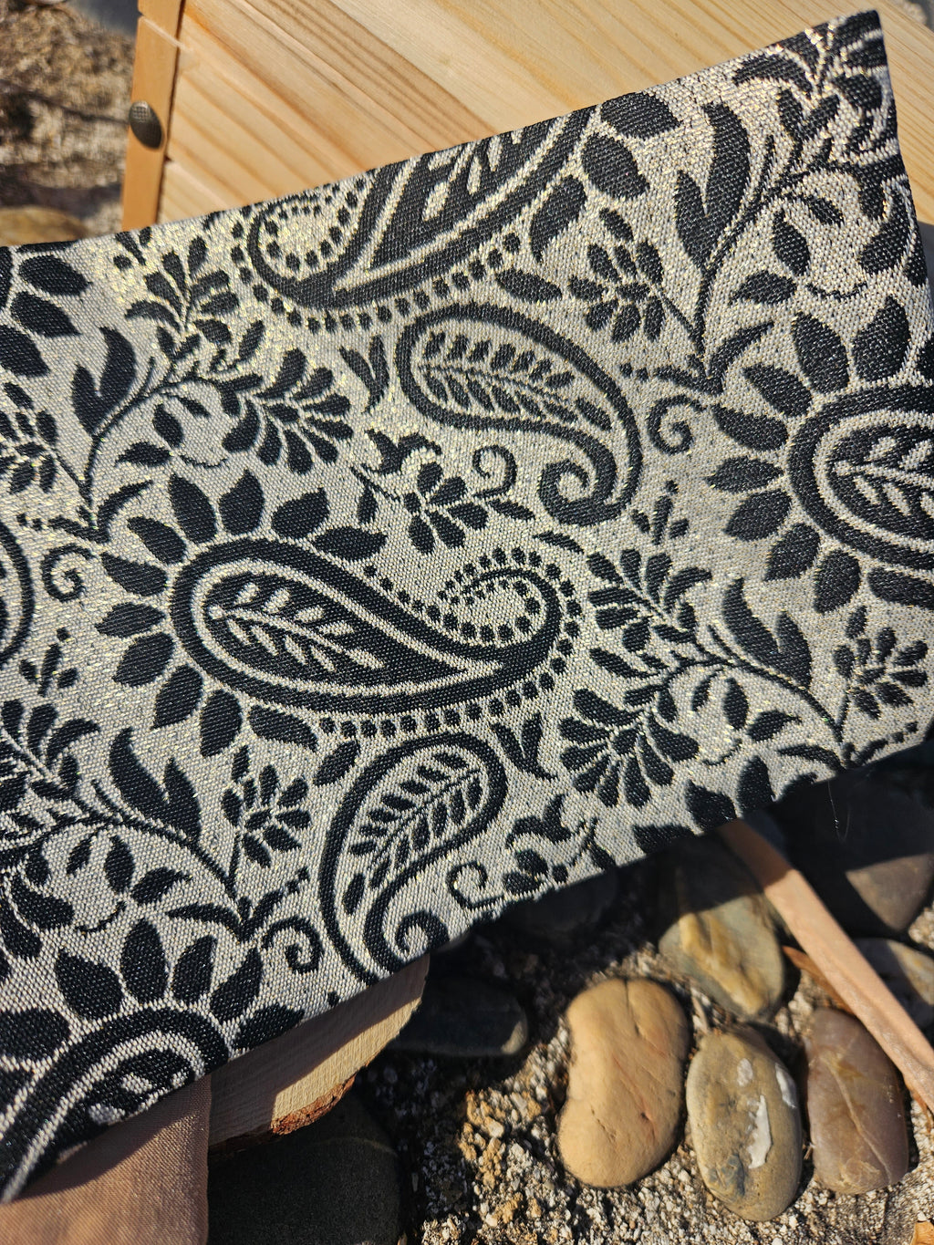 Fajín ancho de tela clara con estampado paisley negro, vista de cerca