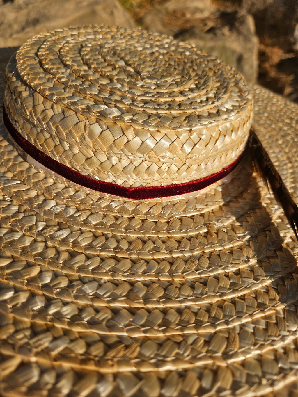 Pamela Siena, sombrero de paja beige con ala ancha y cinta oscura.