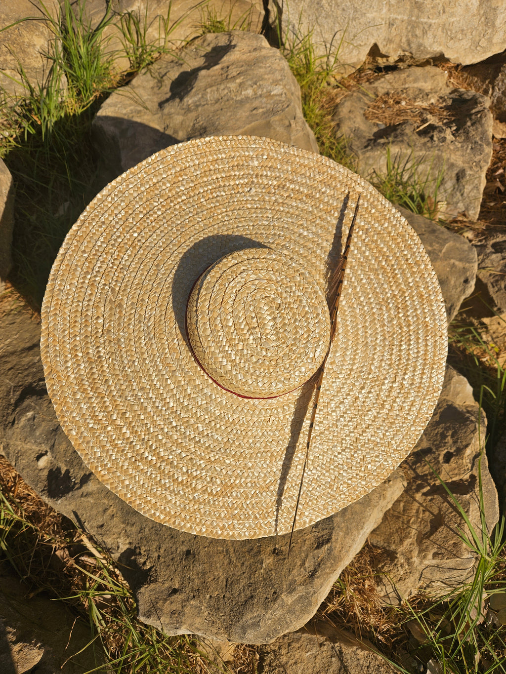 Sombrero de paja beige con ala ancha en vista superior y cinta marrón oscura.