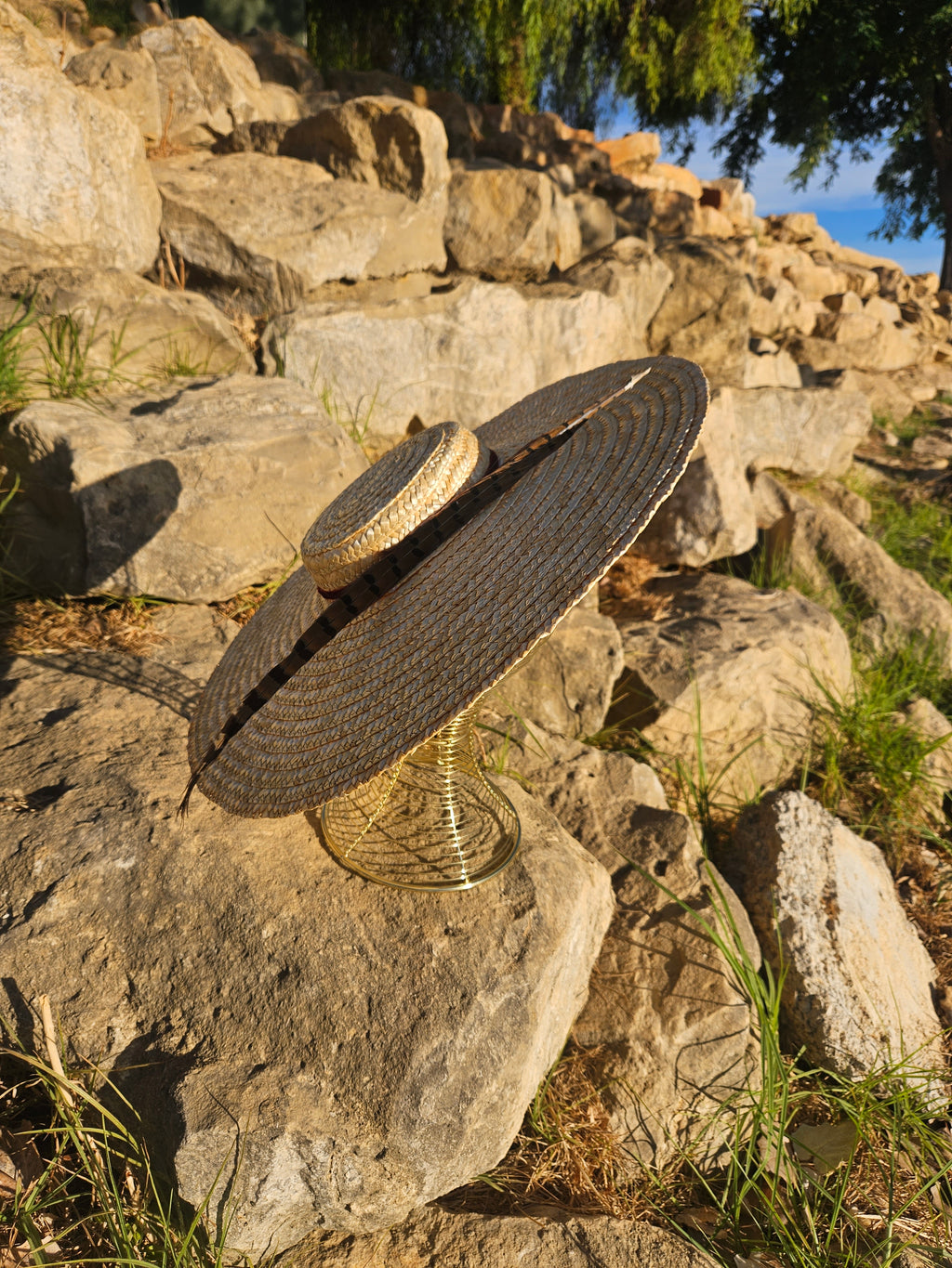 Sombrero de paja beige de ala ancha con cinta oscura, vista inclinada.