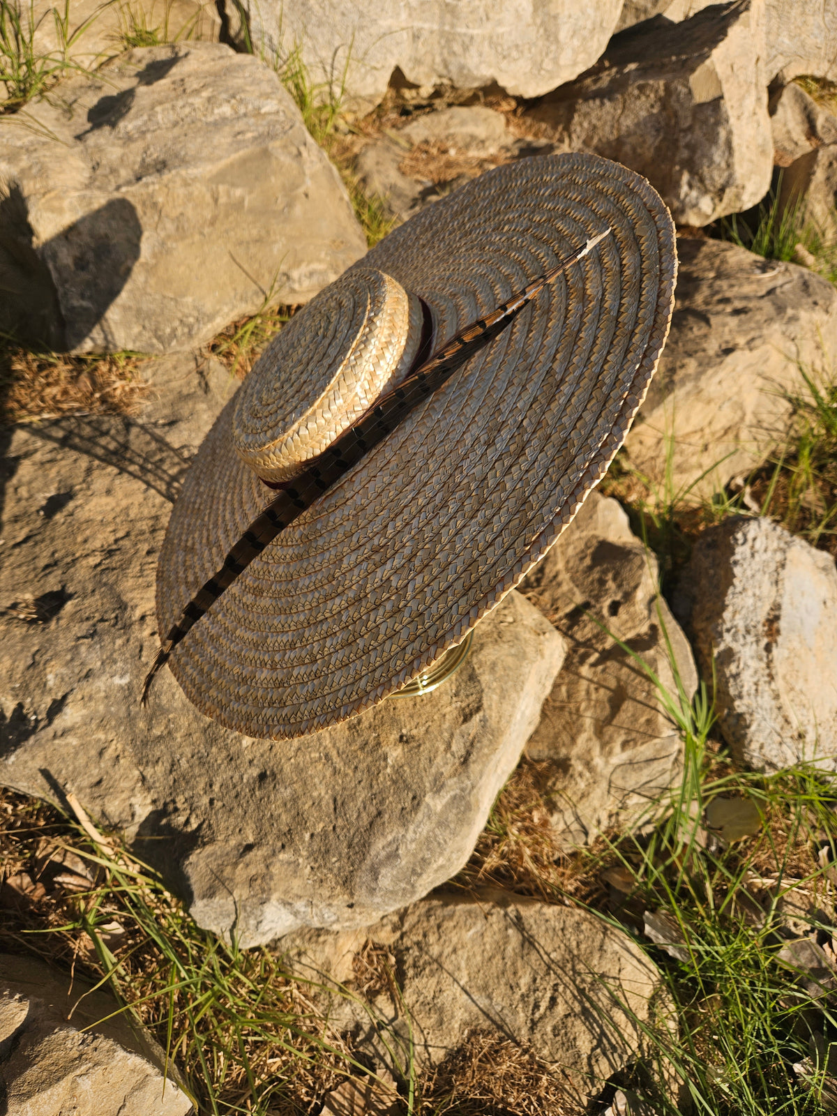 Sombrero de paja beige con cinta oscura y copa redondeada, detalle superior.