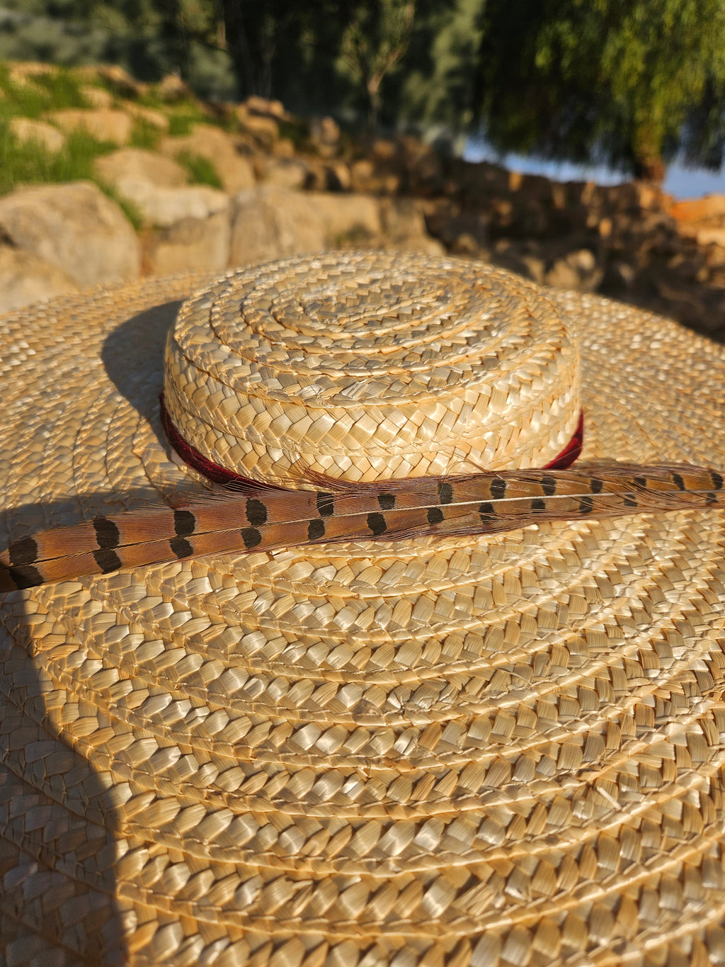 Pamela Siena, sombrero de paja beige con ala ancha y cinta oscura, primer plano.