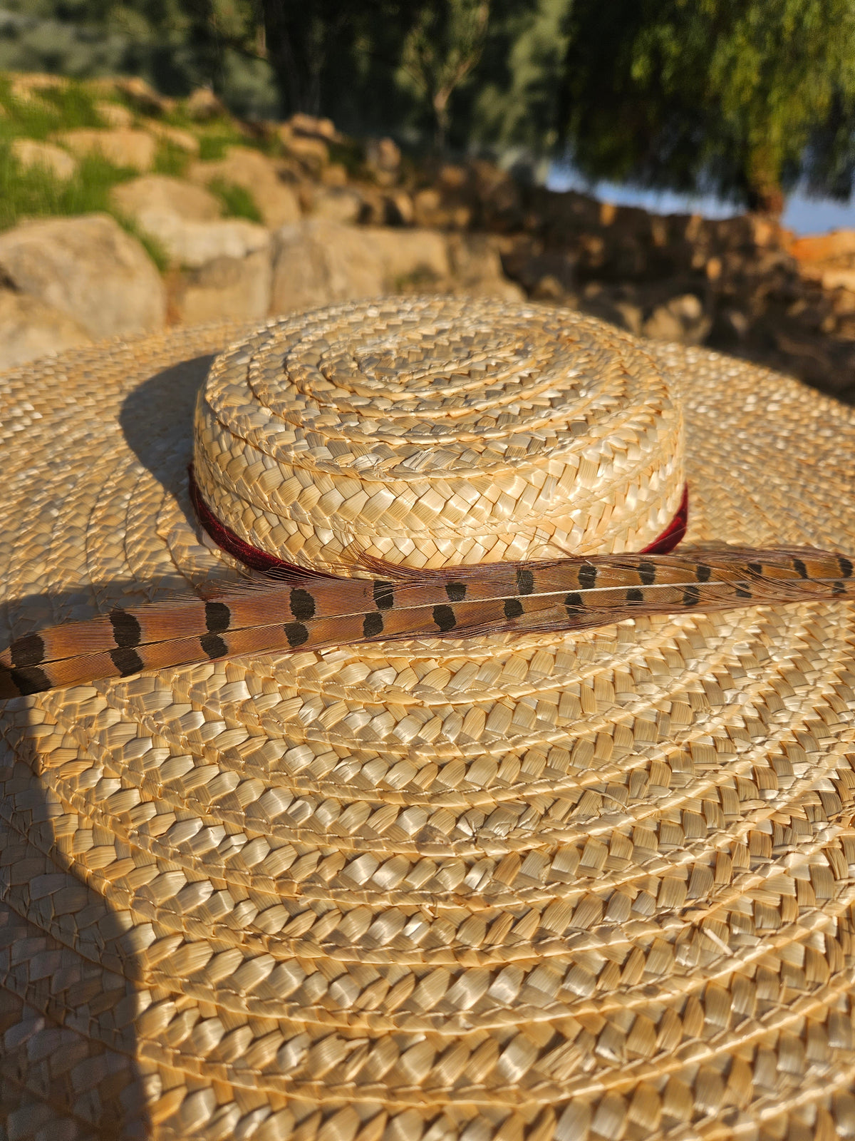 Pamela Siena, sombrero de paja beige con ala ancha y cinta oscura, primer plano.