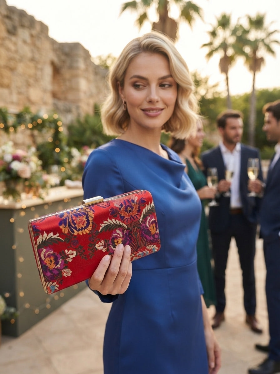 Bolso tipo clutch rojo con bordado floral multicolor y cierre metálico dorado.