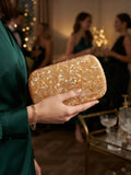 Bolso clutch ámbar con cierre metálico, sostenido en la mano con textura brillante