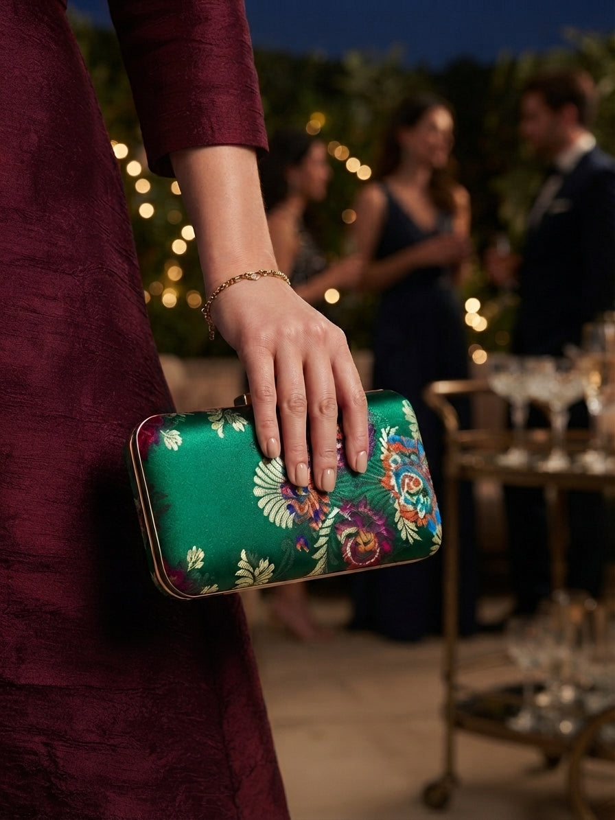 Bolso de mano verde con bordado floral multicolor sujetado con la mano, cierre metálico