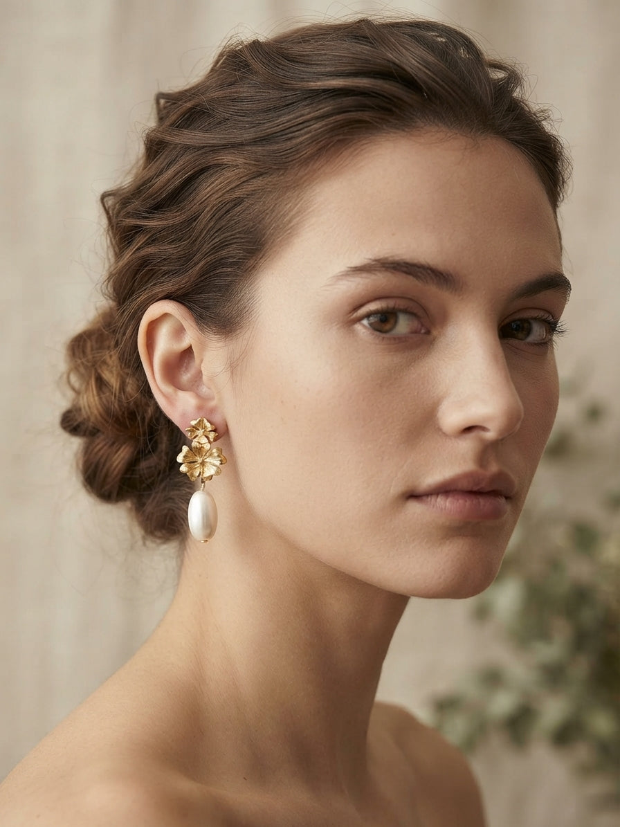Pendientes dorados florales con colgantes blancos tipo perla en la oreja