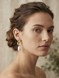 Pendientes dorados florales con colgantes blancos tipo perla en la oreja