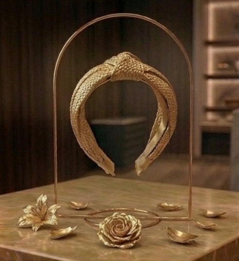Diadema dorada ancha con espirales, sobre mesa