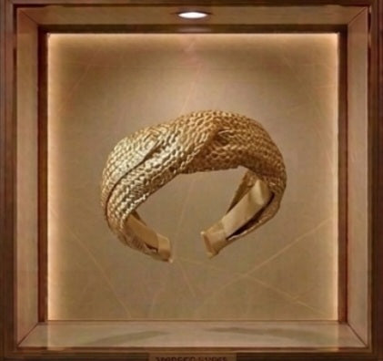 Diadema dorada ancha con textura tejida, vista frontal en vitrina