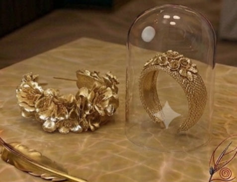 Diadema dorada floral junto a soporte de vidrio, detalle del aro