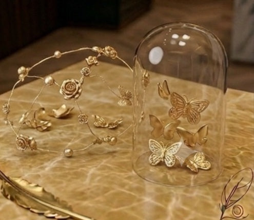 Casquete dorado con apliques florales y mariposas, sobre base de exhibición.