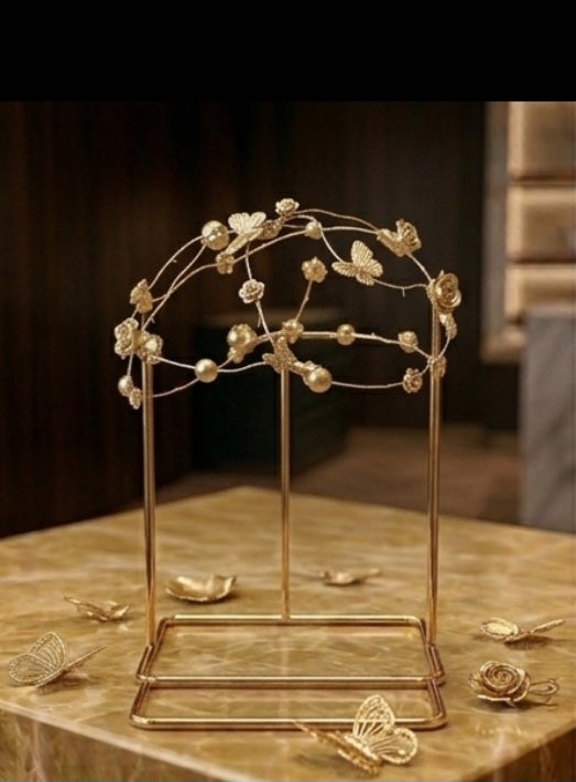 Casquete dorado con corona de mariposas y flores sobre base rectangular.