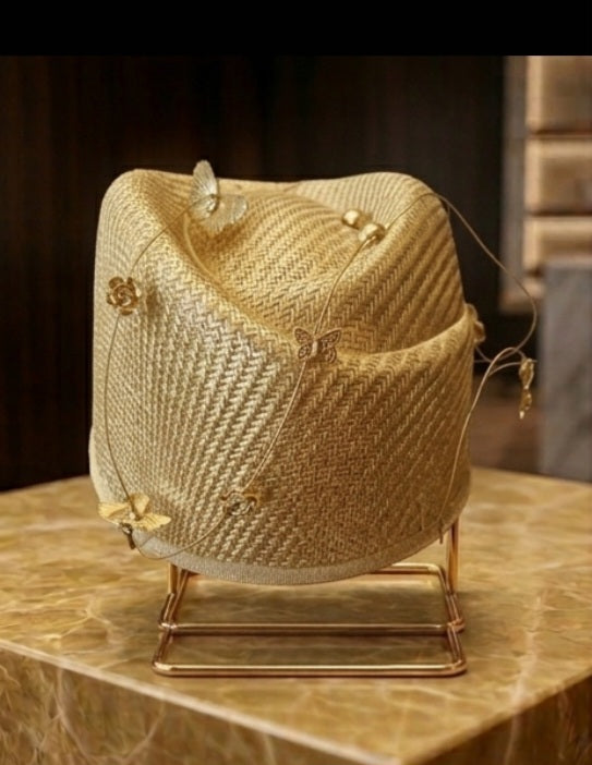 Sombrero de rafia dorada con mariposas y moños, sobre base metálica