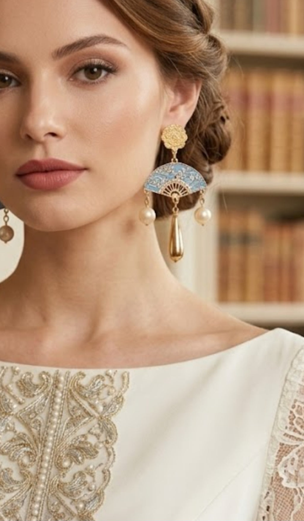 Detalle de pendientes: pieza floral dorada, aro azul y borla con perlas colgantes.
