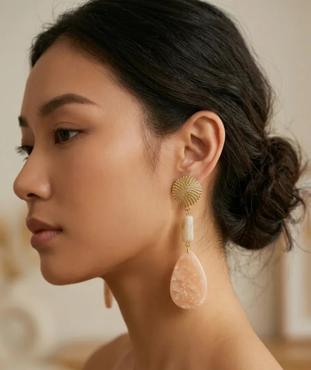 Pendientes dorados con disco tejido y gotas rosa translúcidas en la oreja